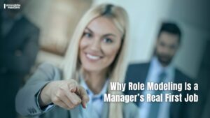 Smiling manager pointing forward with team in background, representing leadership credibility and role modelling in management.