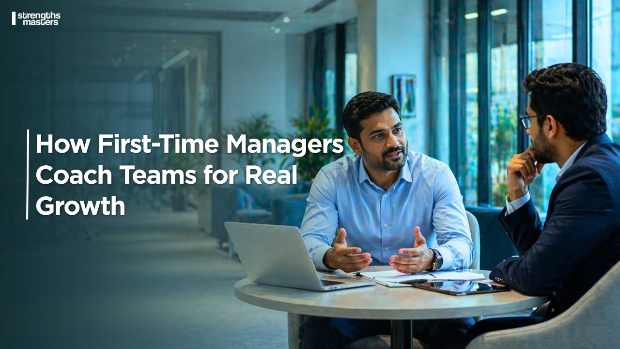 Two professionals in a modern office discussing work at a table with a laptop, alongside text about coaching teams for real growth.